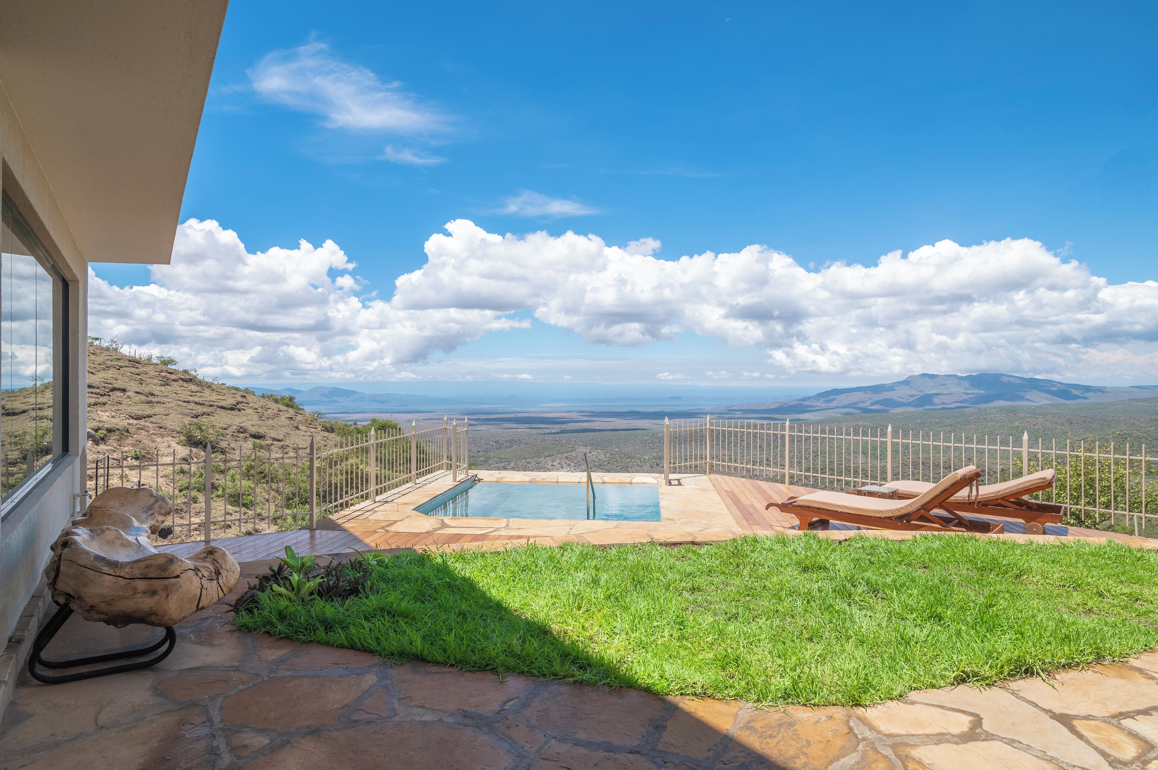 A pool area with lounge chairs, a stone deck, and a view of the mountains.