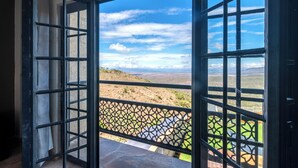 Porta aperta con vista su un balcone che si affaccia su un paesaggio.