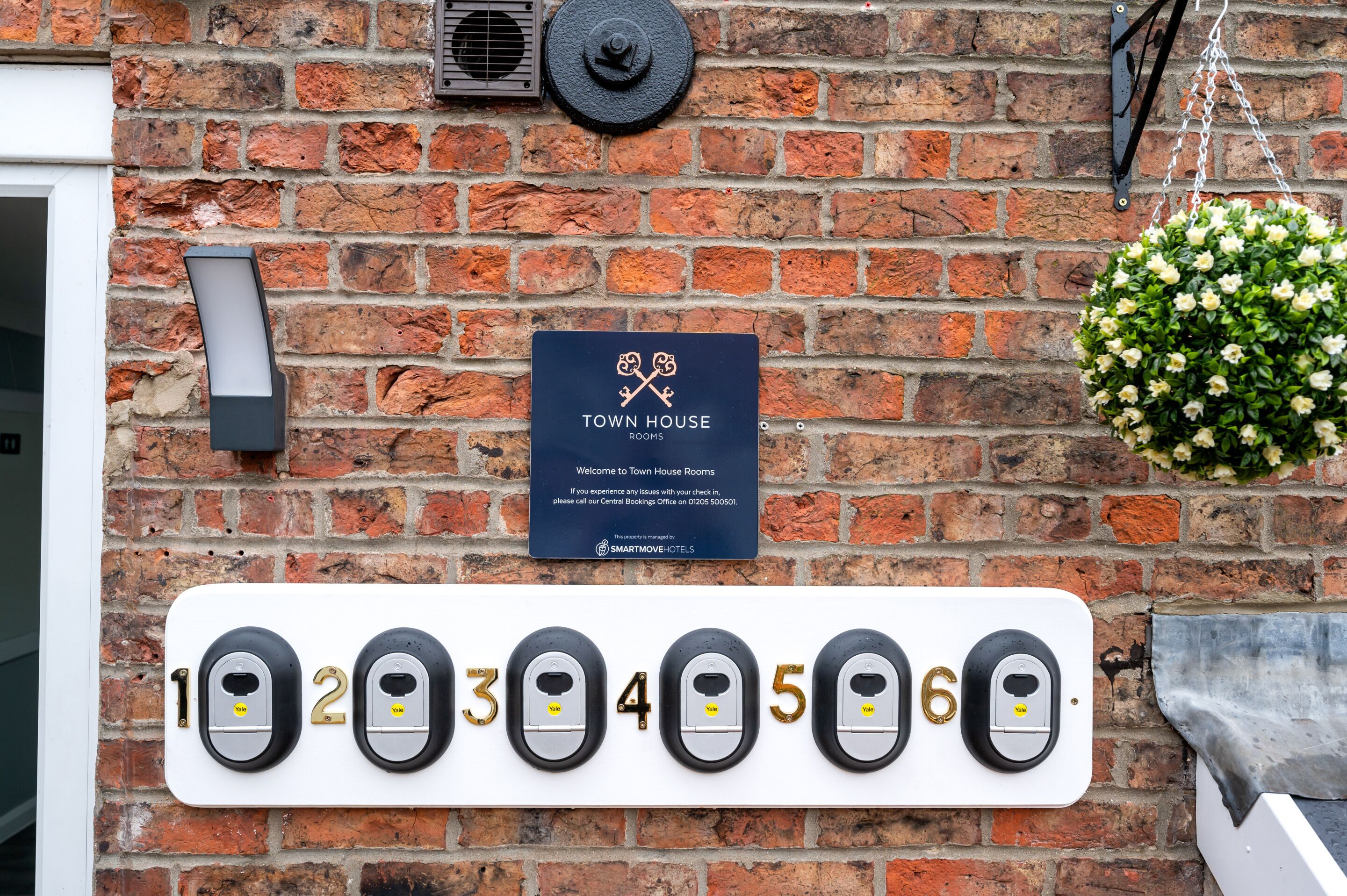 A brick wall with a sign for Town House Rooms, a number plaque, and a doorbell system.