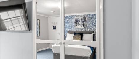 Un dormitorio con cama, ventana y televisor de pared.