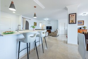 A modern kitchen with a bar area, white bar stools, and pendant lighting. - Fantastic 4 bed apt La Cala Hills (Mijas Costa)