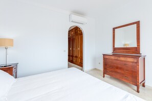 A bedroom with a bed, a dresser with a mirror, an arched doorway, and an air conditioning unit. - Fantastic 4 bed apt La Cala Hills (Mijas Costa)
