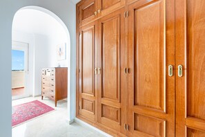 A hallway with a large wooden wardrobe, a small cabinet, and a door leading to a balcony. - Fantastic 4 bed apt La Cala Hills (Mijas Costa)