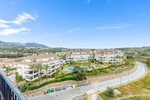 A residential area with multi-story buildings, a curved road, and a distant mountain range.