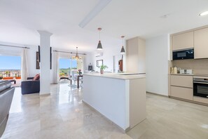 Cocina moderna con isla central, iluminación colgante y vistas al exterior.