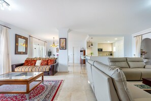 A spacious living room with a sofa, a coffee table, and a rug. There is a kitchen area visible in the background. - Fantastic 4 bed apt La Cala Hills (Mijas Costa)