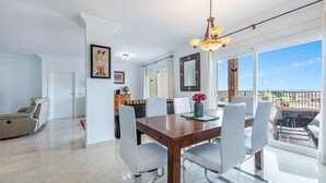 A dining area with a wooden table, white chairs, and a chandelier. - Fantastic 4 bed apt La Cala Hills (Mijas Costa)