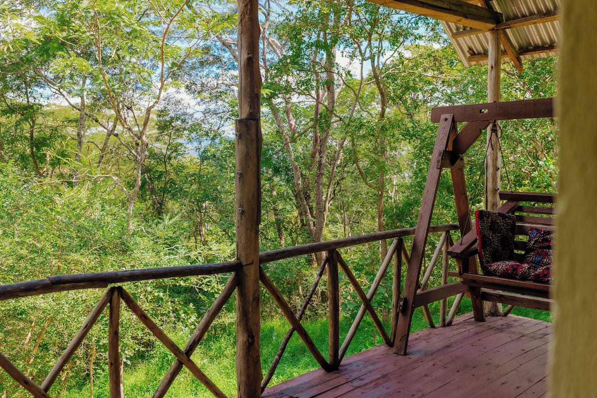 Una terraza de madera con barandilla metálica que da vista a una zona boscosa.
