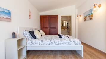 A bedroom with a bed, wooden wardrobe, and a white nightstand.
