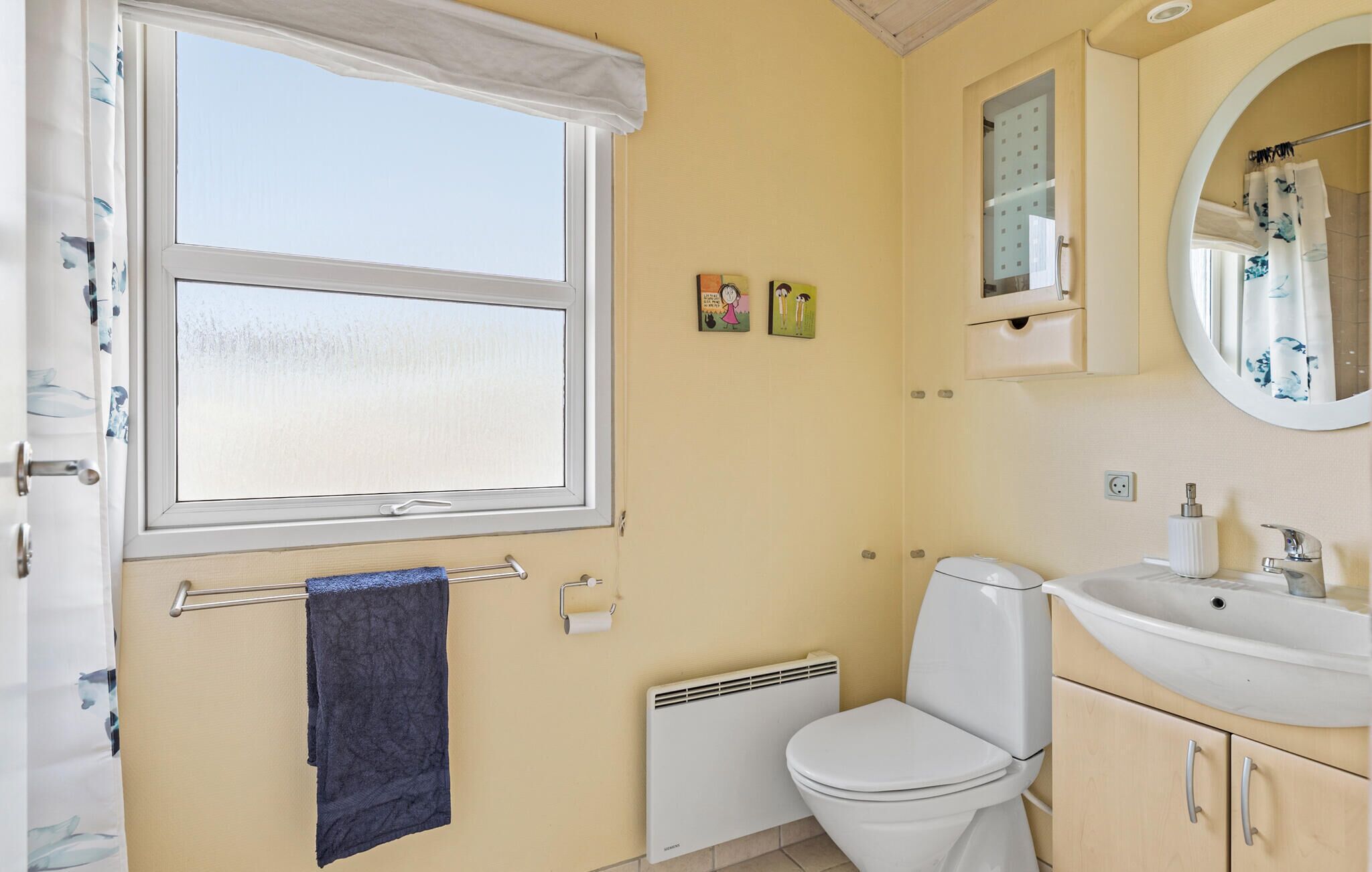 Une salle de bain avec des toilettes, un lavabo et une fenêtre.