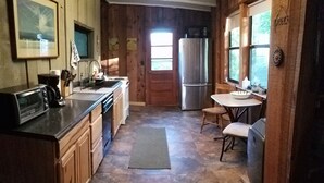 A kitchen with wooden cabinets, a microwave, a refrigerator, and a dining area with a table and chairs. - Beautiful views from cabin in private nature reserve, 10 min to Pigeon Forge (Pigeon Forge)