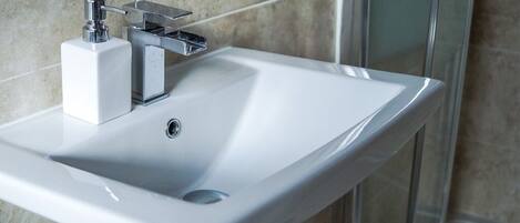 A white bathroom sink with a chrome faucet and soap dispenser.