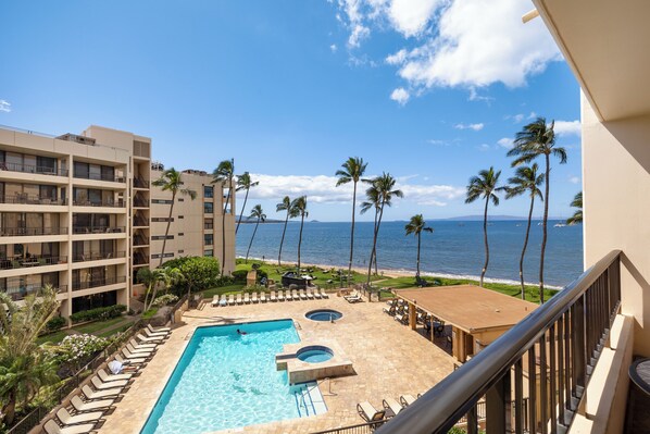 A hotel pool with a view of the ocean and palm trees.