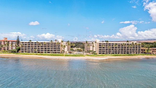 Een hotel aan het strand met meerdere gebouwen, een zandstrand en heldere luchten.