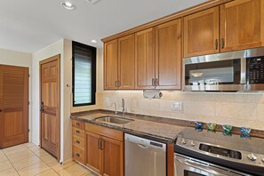 A kitchen with wooden cabinets, a stainless steel microwave, a dishwasher, and an oven. - Stunning Oceanfront 1BR/2BA Retreat with Spectacular Views - Wailea Elua 1802 (Wailea, Maui)