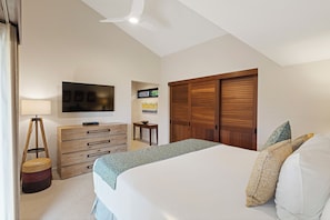 A bedroom with a bed, a dresser, a TV mounted on the wall, and a wooden wardrobe. - Stunning Oceanfront 1BR/2BA Retreat with Spectacular Views - Wailea Elua 1802 (Wailea, Maui)