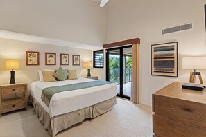 Ein Schlafzimmer mit einem großen Bett, zwei Nachttischen, einem Schreibtisch und Blick ins Freie.