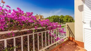 Ein Balkon mit weißer Reling und rosa Bougainvilleenblüten.