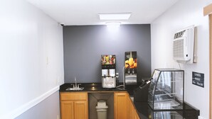 Una cocina compacta con armarios de madera, una cafetera, un refrigerador y una vitrina de vidrio.