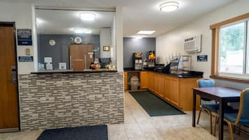 A hotel reception area with a check-in counter, a clock, a phone, and a window with a view of the outdoors.