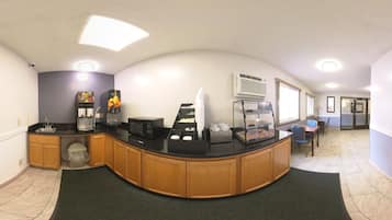 A clean, modern kitchen with a curved counter, coffee machines, and a refrigerator.