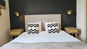 A bed with a beige headboard, two nightstands, and two wall-mounted lamps. - Villa des Baumes (Beaumettes)