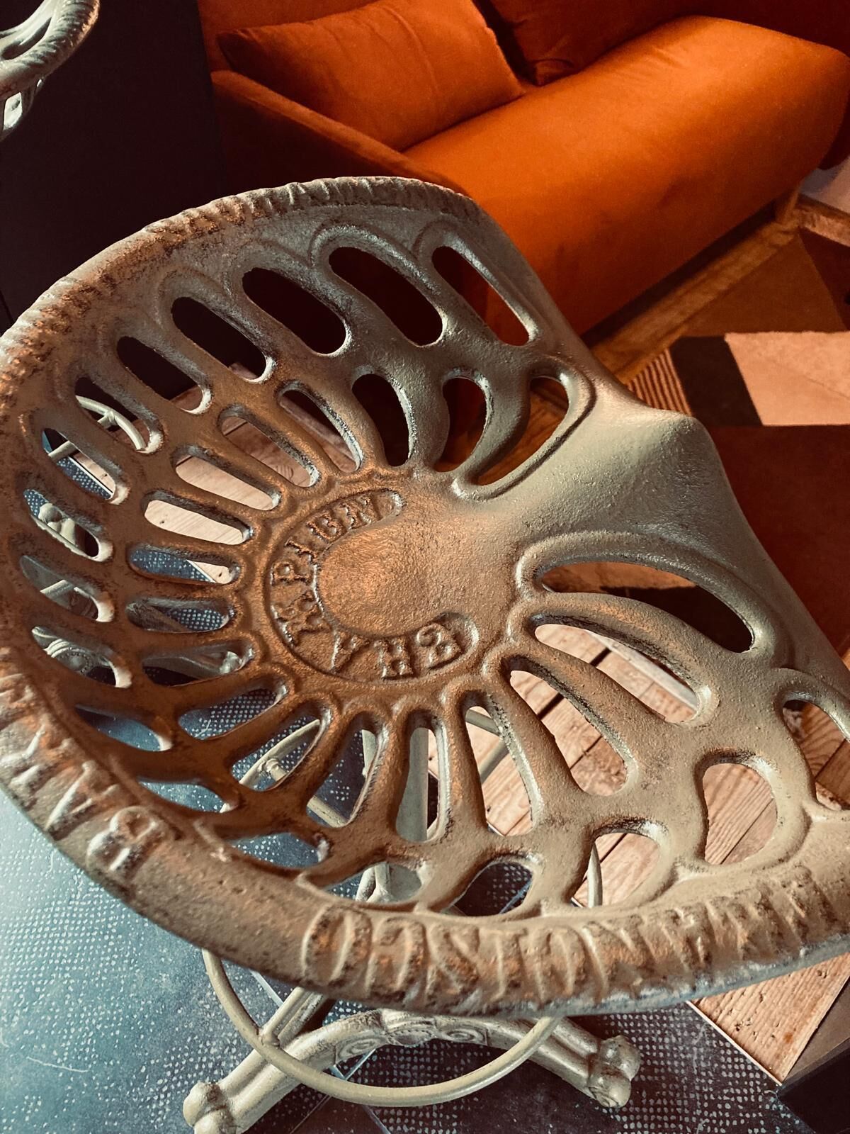 Una cadira de metall amb disseny perforat i un logotip de marca visible.
