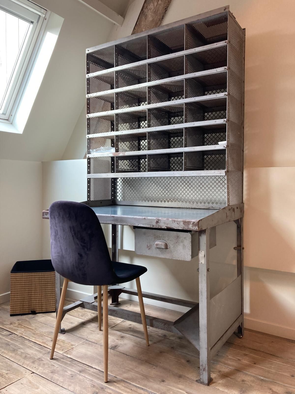 A loft-style room with a metal shelving unit, a dark chair, and a wooden floor.