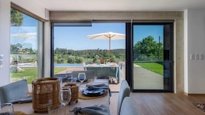 Un comedor con una mesa preparada para cuatro, ventanas amplias y vistas al exterior.