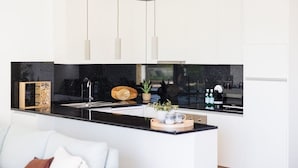 Una cocina moderna con encimera negra, armarios blancos e iluminación colgante.