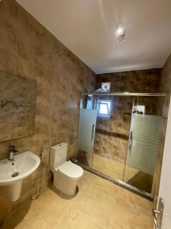 Um banheiro com banheira, vaso sanitário e box de vidro.