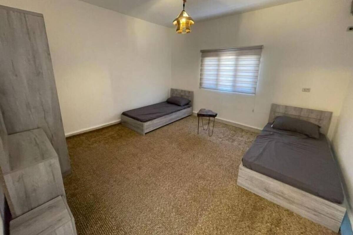 Eine kleine Einzimmerwohnung mit Bett, Sofa, Tisch und einem Fenster mit Jalousien.