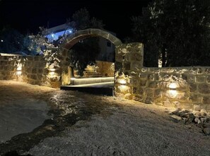 Um arco de pedra que dá entrada a um edifício à noite, iluminado por luzes.
