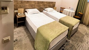 A hotel room with two single beds, a wooden headboard, a small table with a lamp, a nightstand, a thermostat, and a view of the outside through a window with curtains. - EVN Boutique Hotel  (Yerevan)