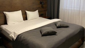 A hotel room with a large bed, dark wood paneling on the walls, a window with sheer curtains, and a nightlight on the wall. - EVN Boutique Hotel  (Yerevan)