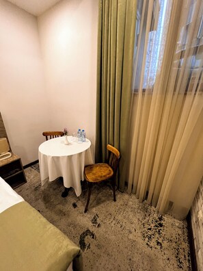 A hotel room with a round table, two chairs, a bed, a nightstand, a lamp, and a window with curtains. - EVN Boutique Hotel  (Yerevan)