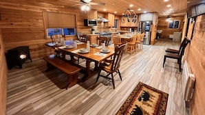 A cozy wooden cabin interior with a dining area, kitchen, and a fireplace. - 12 miles from Yellowstone with incredible views - Grizzly Lodge (Island Park)