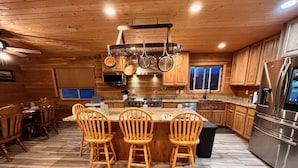 A wooden interior with a kitchen island, chairs, and a refrigerator. - 12 miles from Yellowstone with incredible views - Grizzly Lodge (Island Park)
