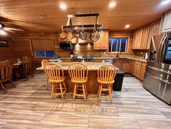 A wooden interior with a kitchen island, chairs, and a refrigerator. - 12 miles from Yellowstone with incredible views - Grizzly Lodge (Island Park)