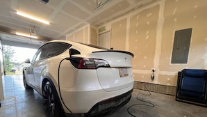 A white car parked in a garage with unfinished walls and a blue chair. - 12 miles from Yellowstone with incredible views - Grizzly Lodge (Island Park)