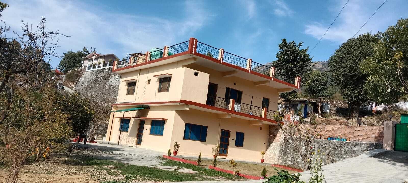 A two-story building with a balcony, a small garden area, and a clear sky.