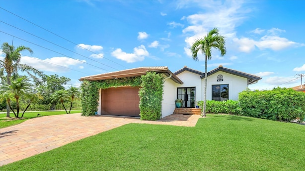 A two-story house with a garage, a well-maintained lawn, and a palm tree.