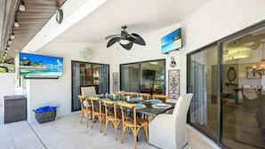 A dining area with a table set for six, a ceiling fan, and a television mounted on the wall.