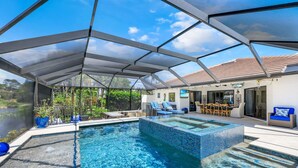 A swimming pool with a glass enclosure, surrounded by outdoor furniture and a covered patio area.