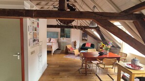 A cozy attic room with a wooden dining table, chairs, and a view of the bedroom below. - Luxe Appartement in het Oude Centrum (Zutphen)
