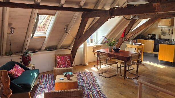A loft-style room with a dining area, a kitchen in the background, and a view of the outside through a skylight. - Luxe Appartement in het Oude Centrum (Zutphen)