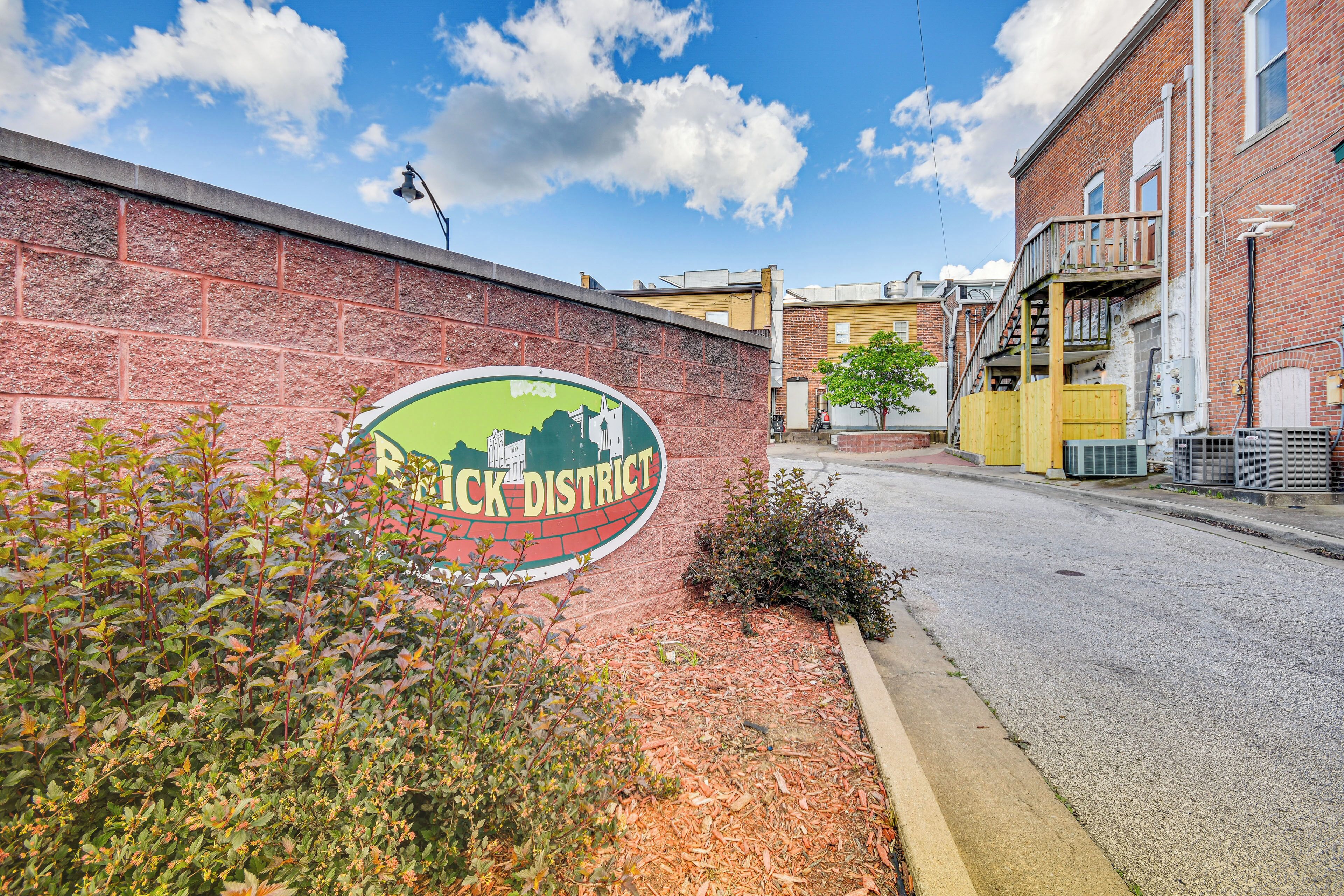 A brick wall with a sign for "Black District" and a street view with buildings and a clear sky.