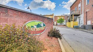 A brick wall with a sign for "Black District" and a street view with buildings and a clear sky.