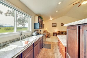 A kitchen with a large window, wooden cabinets, a built-in oven, and a countertop with a sink. - Cozy Clearwater Apartment - Hike, Fish & Explore! (Stites)