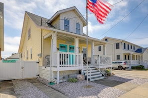 A two-story house with a porch, a flag, and a driveway.